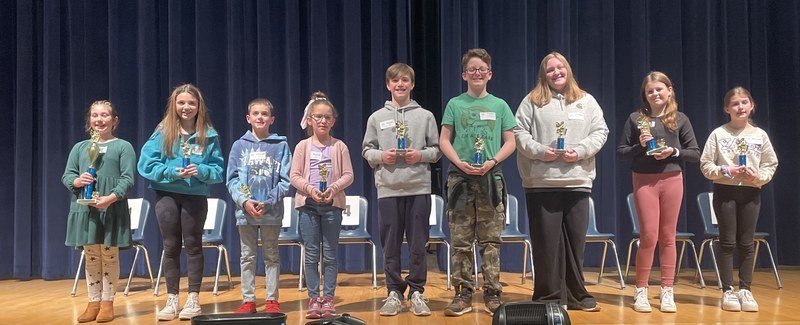 students holding trophies after winning the spelling bee