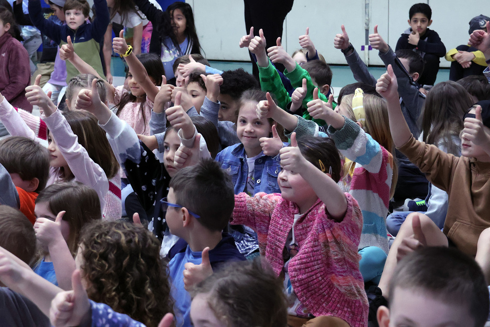 Clayville students at an assembly give a thumbs up